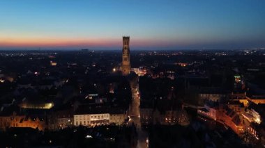 Güneş tarihi bina ve kanalların üzerinde batarken Brugge, Belçika 'nın nefes kesici hava perspektifinin tadını çıkarın. Parıldayan ışıklar arasında parlayan şehrin büyülü akşamını gözler önüne seriyor..