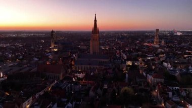 Brugge, Belçika 'nın güzelliğini bu büyüleyici şehrin üzerinde güneş batarken tecrübe edin. Ortaçağ binalarını ve kanallarını keşfeder altın ışıkla yıkanmış, eşsiz manzarasını ön plana çıkarır..