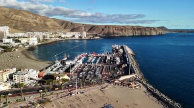 Tenerife 'deki Los Cristianos' un canlı marinası, kumlu sahili ve çevresindeki dağların nefes kesici manzarasının tadını çıkarın. Burası rahatlamak ve kıyı boyunca manzaralı yürüyüşler için mükemmel bir yer..