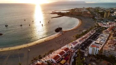 Tenerife 'deki Los Cristianos plajında gün batımını izle. Gemiler suyu noktalarken gökyüzü canlı renklerle dönüyor, sakin bir atmosfer ve manzaralı görüntüler sağlıyor..