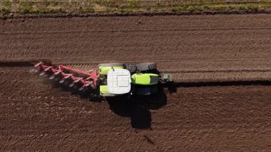 Güçlü bir traktör bahar ekimi için kırsal bir alanda toprağı özenle hazırlamak için çalışır. Güneşli bir gün tarımsal faaliyet için ideal bir ortam yaratıyor..