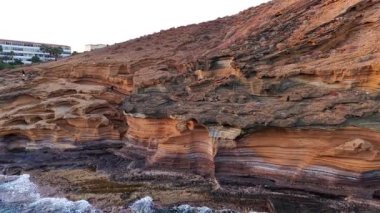 Tenerifes kıyı şeridinin nefes kesici hava perspektifini deneyin, canlı kaya katmanlarını ve sakin okyanusu vurgulayın. Çarpıcı manzara adaların doğal cazibesini yansıtıyor..