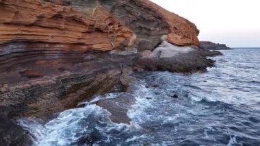 Bu çarpıcı hava manzarası Tenerife 'nin dramatik uçurumlarını yakalar ve berrak Atlantik sularına karşı günbatımının canlı renklerini yansıtır. Adaları keşfedin doğal güzellikleri.