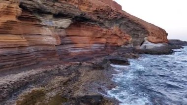 Tenerife 'nin dramatik sahil şeridini, derin mavi sularla zıt dünyevi tonlarda kayalıklarla keşfedin. Dalgaların alacakaranlıkta kayalık kıyıya nazikçe dokunuşuna tanık olun..