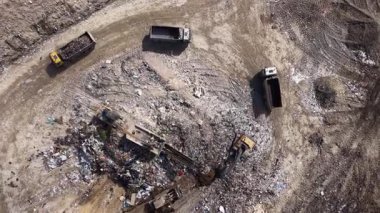 Video, atık işleme tesislerinin günlük faaliyetlerini ve birden fazla kamyonun atık boşaltmasını gösteriyor. Ağır makineler, kentsel bir ortamda atık maddeleri aktif olarak sınıflandırıyor ve işliyor.