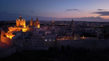 Gece çökerken Mdina 'nın büyülü atmosferini hissedin, tarihi binaları ve narin ışık yansımalarını vurgulayın. Cazibe ve geçmişle dolu dar sokaklarda dolaş..