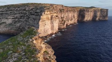 Gün batımında Malta 'nın nefes kesici uçurumlarına ve turkuaz sularına tanık olun. Bu hava keşfi adaların dramatik manzarasını ve sakin ortamını vurguluyor..