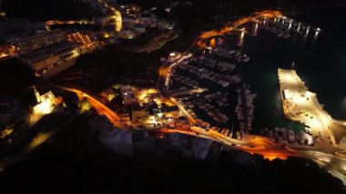 Maltas marinasının gece gökyüzüne karşı güzelce aydınlatılmış yat ve teknelerle dolup taşan nefes kesici hava perspektifini tecrübe edin. Rıhtımın cazibesini ve canlılığını keşfedin..