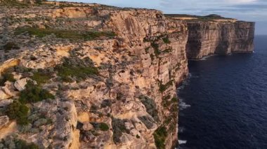Malta 'nın göz kamaştırıcı güzelliğini yukarıdan deneyimleyin. Derin mavi denizle karşılaşan görkemli uçurumları görün. Günbatımının altın renkleri manzarayı aydınlatır ve sakin bir atmosfer yaratır..