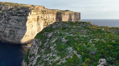 Yukarıdan Malta 'nın nefes kesici uçurumlarını keşfedin, canlı yeşillik ve masmavi suları ortaya çıkarın. Manzara, eşsiz jeolojik oluşumları ve dingin güzelliği vurgular..