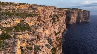 Güneş ufukta batarken Malta 'nın muhteşem uçurumlarını keşfedin. Doğal güzellik ve engebeli manzara adaların cazibesini ve eşsiz coğrafyasını vurgular..
