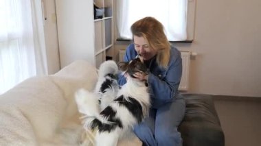 Bir kadın, rahat bir oturma odasında neşeli bir köpekle keyifli vakit geçirir. Sevgi dolu bir oyun oynarlar, bağlarını ve ev hayatının sıcaklığını gösterirler..