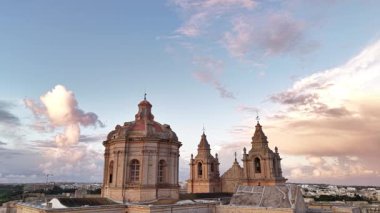 Mdina, Malta 'nın antik şehrini keşfedin, altın güneş ışığı muhteşem kubbeleri ve kuleleri yıkarken, bu büyüleyici yerin zengin tarihini ve cazibesini gözler önüne seriyor..