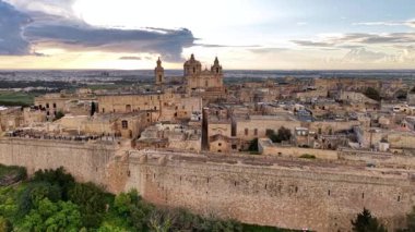 Mdina 'nın nefes kesici güzelliğini, antik duvarların ve tarihi binaların gün batımının canlı renkleriyle buluştuğu yerden deneyimleyin. Bu büyüleyici görüntüde Maltas 'ın zamansız cazibesini keşfet.