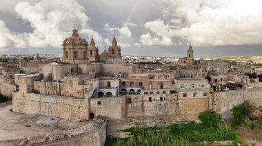 Mdina 'nın büyüleyici güzelliğini yukarıdan deneyimleyin, antik duvarlar ve görkemli binalar manzaralı bir ufka karışarak, tarih ve doğa senfonisi oluşturur..