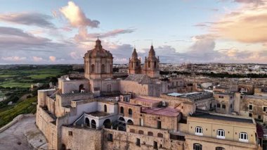 Mdina 'nın büyüleyici güzelliğine yukarıdan tanık olun. Altın gün batımı, tarihi binalara ve yemyeşil çevrelere sıcak bir ışık tutuyor. Maltas' ın eski başkentinde büyülü bir atmosfer yaratıyor..