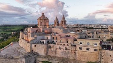 Mdinas 'ın görkemli ufuk çizgisinin nefes kesici hava manzarasını deneyimleyin. Tarihi mimarisi ılık altın ışıkla yıkanmış. Huzurlu ortam bu antik şehrin özünü yansıtıyor..