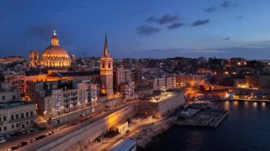 Güneş Malta 'nın üzerinde batarken Valletta' nın çarpıcı hava manzarasını izleyin. Tarihsel mimari alacakaranlık altında parlar ve canlı sahil kıyısı ışıklarla canlanır..