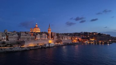 Alacakaranlık çöktüğünde Malta 'daki Valletta' nın çarpıcı hava manzarasını deneyimleyin. Tarihi binalar akşam ışıklarının altında ışıldıyor, limanın üzerinde pitoresk bir ufuk çizgisi sunuyor..