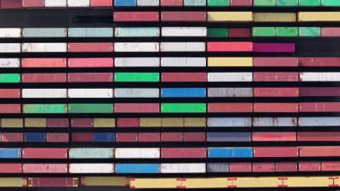 Brightly colored shipping containers are stacked in organized rows at Zeebrugge port, showcasing the busy maritime activity. The vibrant patterns create a striking visual against the clear sky.