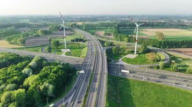 Büyüleyici bir hava perspektifi, Brüksel yakınlarındaki yemyeşil ve yel değirmenleriyle çevrili yoğun bir yol kavşağını gözler önüne seriyor..