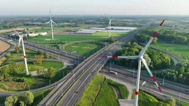 Bruges yakınlarındaki bir yol kavşağında, yenilenebilir enerji kullanan çok sayıda yel değirmeninin çarpıcı bir hava manzarası keşfedin. Bu manzara doğa ve modern altyapıyı güzel bir şekilde birleştiriyor..