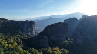 Meteora 'nın, yüksek kaya oluşumlarının uzak dağların arka planında canlı yeşil ormanlarla buluştuğu Yunanistan' da nefes kesici hava manzarası. Doğa güzelliği bekliyor..