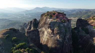 Çarpıcı Meteora bölgesinin çok yukarısında, yükselen kaya oluşumlarının tepesinde tünemiş antik manastırların dingin güzelliğini deneyimlediler. Güneşin altın rengi manzarayı güzelleştirir..