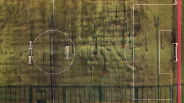 Girit 'teki bir futbol maçının heyecanını hava perspektifinden yaşayın. Parlak bir gökyüzü altında oyuncuları verimli bir sahada sergiliyor..