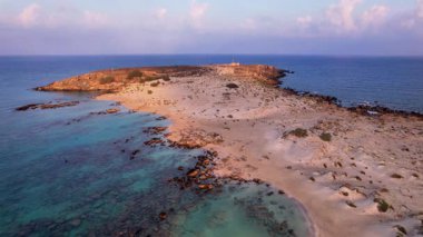 Yunanistan 'ın Girit kentindeki Elafonissi Sahili' nin güzelliğini yukarıdan deneyimleyin. Eşsiz pembe kumlarını ve turkuaz sularını altın saat boyunca parlak bir gökyüzünün altında keşfedin..
