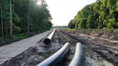 Bu inşaat projesinde ağaçlarla çevrili temiz bir patika boyunca bir gaz boru hattı kurulumu yer alıyor..