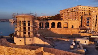 Valetta, Malta 'nın çarpıcı hava perspektifini deneyin, tarihi binaları, deniz manzaralarını ve devam eden inşaatı vurgulayın. Gün batımında bu canlı şehrin güzelliğini keşfedin..