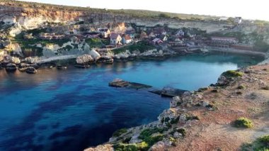 Malta 'daki büyüleyici bir balıkçı köyünün nefes kesici hava manzarasını tecrübe edin. Kıyıdaki kayalıkları keşfedin, sakin suları, ve güzel güneşli bir günde sahil boyunca yuva yapmış ilginç binaları..