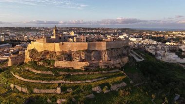 Gozo, Malta 'daki Hisar' ın nefes kesici hava perspektifine tanık olun. Bu tarihi mekan, canlı bir günbatımının arkaplanına karşı, mimari ihtişamını gözler önüne seriyor..