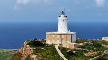 Maltas ikonik deniz fenerinin kristal berrak sular ve yemyeşil manzaralarla çevrili engebeli sahil şeridine tünediğini hayal edin..