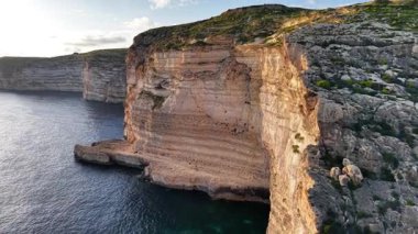 Güneş sakin suların üzerinde batarken Malta 'nın nefes kesici uçurumlarına hayret ediyorum. Bu güzel adayı tanımlayan eşsiz kaya oluşumlarını ve sakin kıyı şeridini keşfedin..