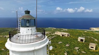 Uçsuz bucaksız Akdeniz ve yemyeşil çevreye tepeden bakan tarihi bir deniz fenerini aydınlatan, sakin Maltas manzaralarını gösteren çarpıcı hava manzaralarını keşfedin..