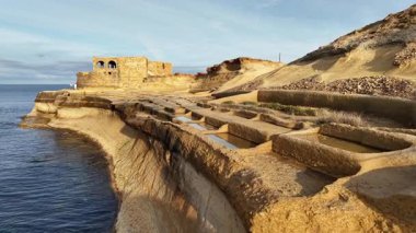 Güneş batarken Malta 'nın güzelliğini keşfedin büyüleyici sahil kayalıklarını, tarihi yapıları ve berrak mavi suları gösterin. Doğal harikaların sakin bir hava perspektifi..