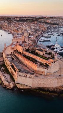 Valletta, Malta 'nın nefes kesici hava manzarasını keşfedin, ikonik tahkimatlarını, deniz kenarını ve güzel günbatımını sergileyin. Limana yansıyan canlı renkleri keşfedin.