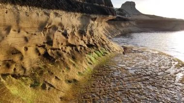 Güneş çarpıcı sahil kayalıklarının üzerinde batarken Malta 'nın nefes kesici hava manzarasını deneyimleyin. Zengin dokular ve renkler engebeli manzarayı aydınlatıyor, güzellikleri gözler önüne seriyor..