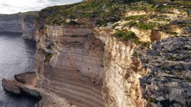 Maltas 'ın dramatik sahil uçurumlarının güzelliğini yukarıdan görün. Denizin canlı renklerinin ve gün ışığında kıyı şeridini çevreleyen yemyeşil manzaraların tadını çıkarın..