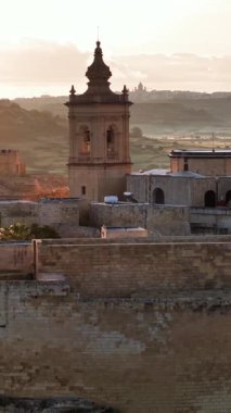 Malta 'nın çarpıcı adası Gozo' da bulunan Hisar 'ın nefes kesici hava perspektifini tecrübe edin. Zengin tarih güzel bir şekilde sergileniyor. Güneş batarken, antik duvarları aydınlatıyor..