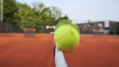 Güneş parlak turuncu kille kaplı canlı bir tenis kortunun üzerinde batar. Yeşillik ağaçlar, oyuncular en iyi öğleden sonra saatlerinde rekabetin tadını çıkarırken gölge sağlar..