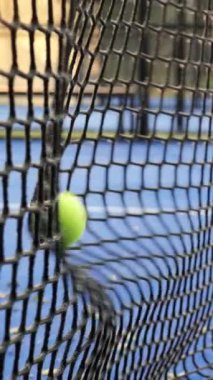 Oyuncular tenis yeteneklerini mavi bir kortta, parlak yeşil bir top ağlara çarptığında, tekniklerini geliştirme amaçlı bir eğitim oturumunun önemli bir anını sergiliyorlar..