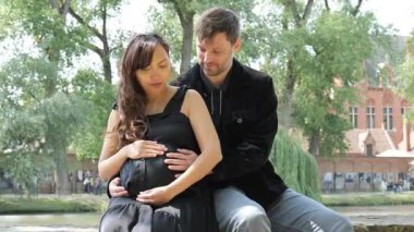 Sevgi dolu bir çift, parkta sakin bir öğleden sonra geçirir ve hamilelik yolculuklarını kucaklarlar. Koca, karısının karnına nazikçe dokunurken kadın neşe saçıyor..