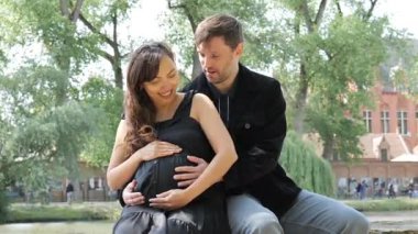 Sevgi dolu bir çift parkta huzurlu bir anın tadını çıkarırken hamile kadın ışıl ışıl gülümsüyor. Yeşillik ve güneş ışığı birlikte geçirdikleri özel zamanlar için sıcak bir atmosfer yaratıyor..