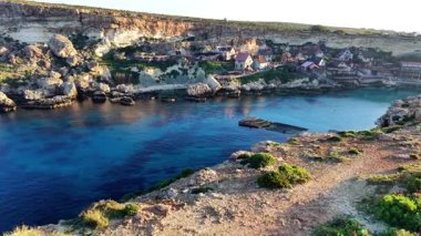 Malta 'da güzel bir balıkçı köyünün güzelliğini keşfedin. Evlerin, sakin suların ve ılık güneş ışığında yıkanan engebeli kayalıkların olduğu bir yer. Huzurlu sahil cazibesini dene..