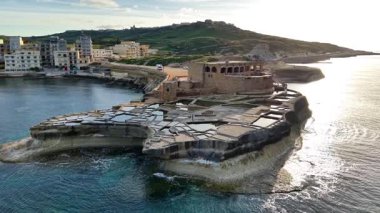 Maltas tuz tavalarının nefes kesici hava manzarasını, gün batımının sıcak parıltısını yansıtan karmaşık desenlerini deneyimleyin..