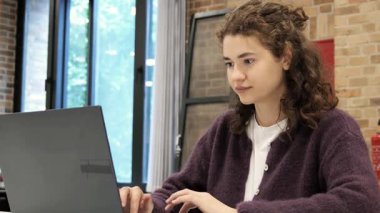 Doğal ışıkla dolu geniş bir kütüphanede, laptopta odaklanmış bir öğrenci, sakin bir öğleden sonra araştırma ve akademik görevleriyle meşgul olur..