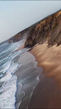 Güney Portekiz 'in görkemli sahil şeridini deneyin dramatik uçurumlar ve altın kumlu plajlar. Dalgalar kıyıya vuruyor, güneş batarken doğal güzellikleri vurguluyor..